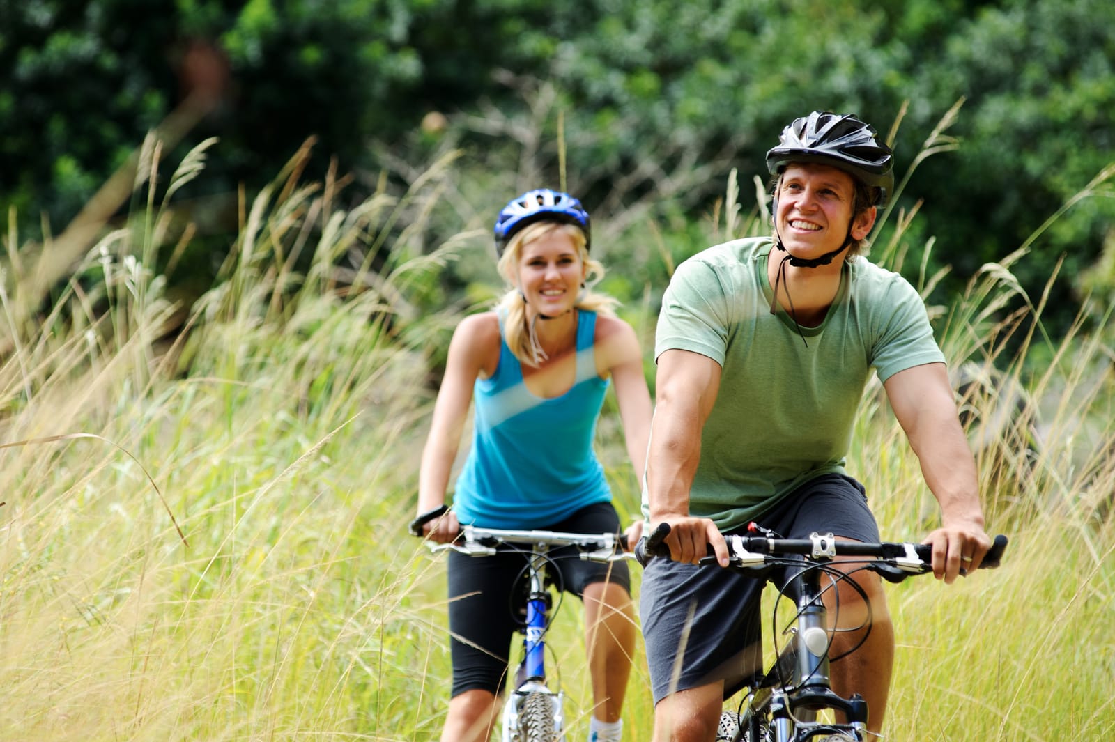 Couple Cycling Through Grass