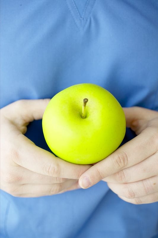 Hands Holding Green Apple Scrubs