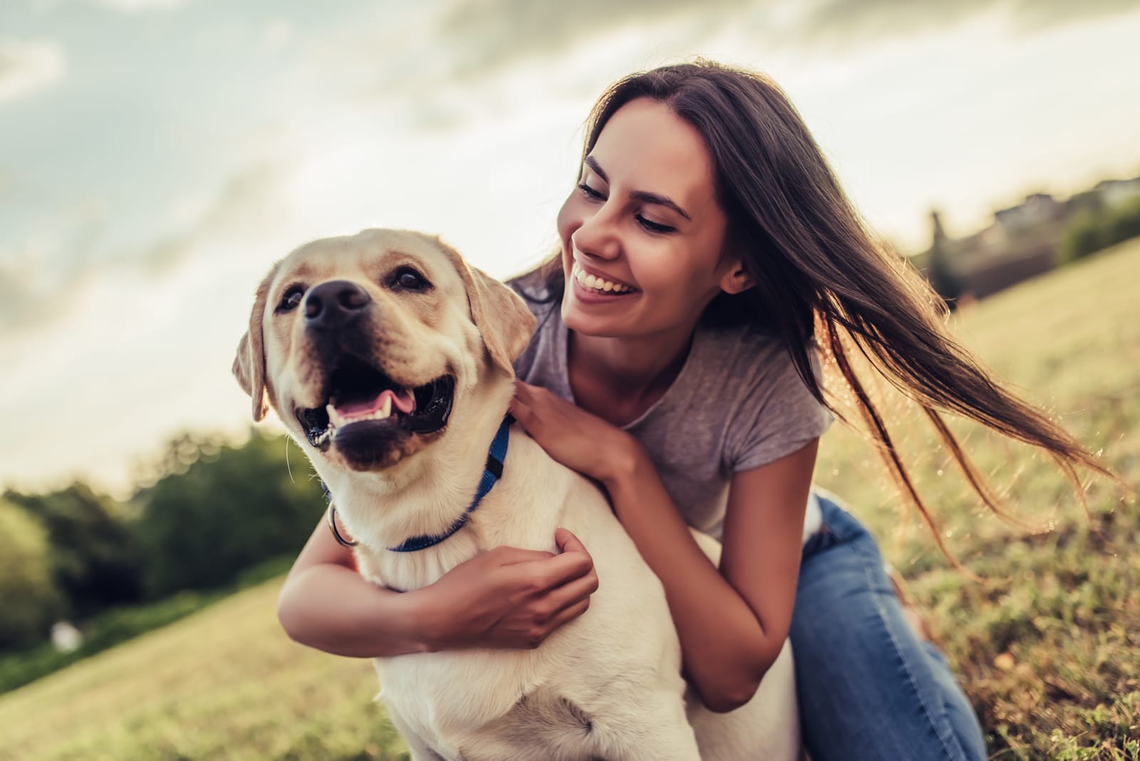 Woman Hugging Labrador Dog Outdoors