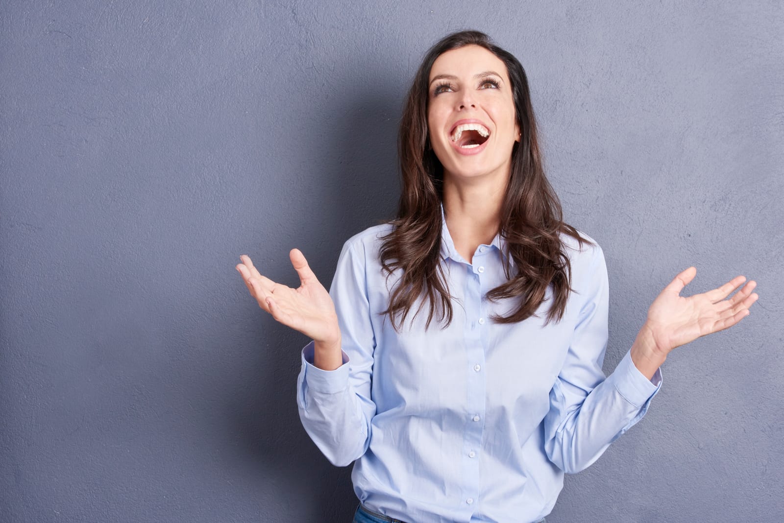 Woman Laughing Hands Up Gray Wall