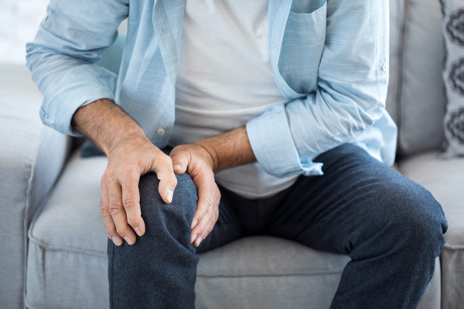 Man Holding Knee Pain Sofa